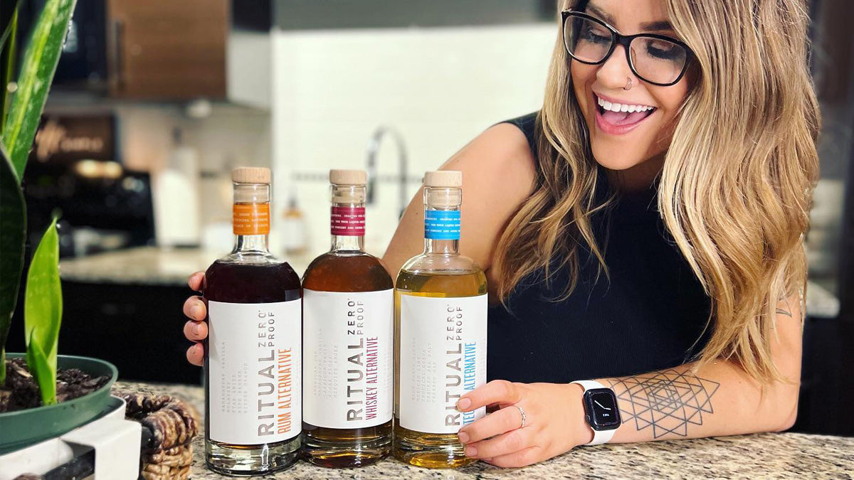 Woman holding bottles of Ritual Zero Proof rum alternative, whiskey alternative, and tequila alternative