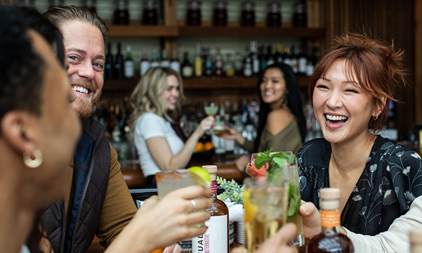 People at a restaurant with cocktails laughing
